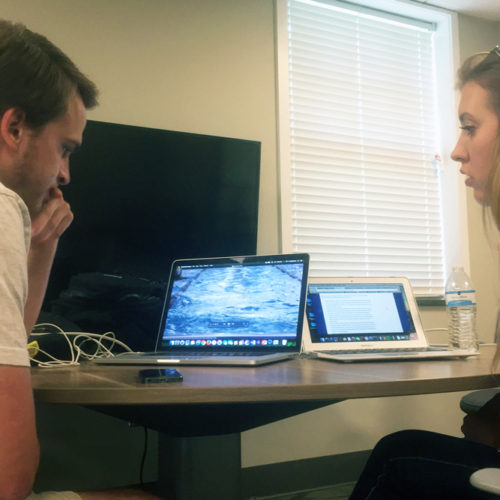 Queens students Austin Huddy and Caroline Henry discuss a multimedia piece on U.S. Olympic swimming coach David Marsh by speakerphone with student Abby Tolar