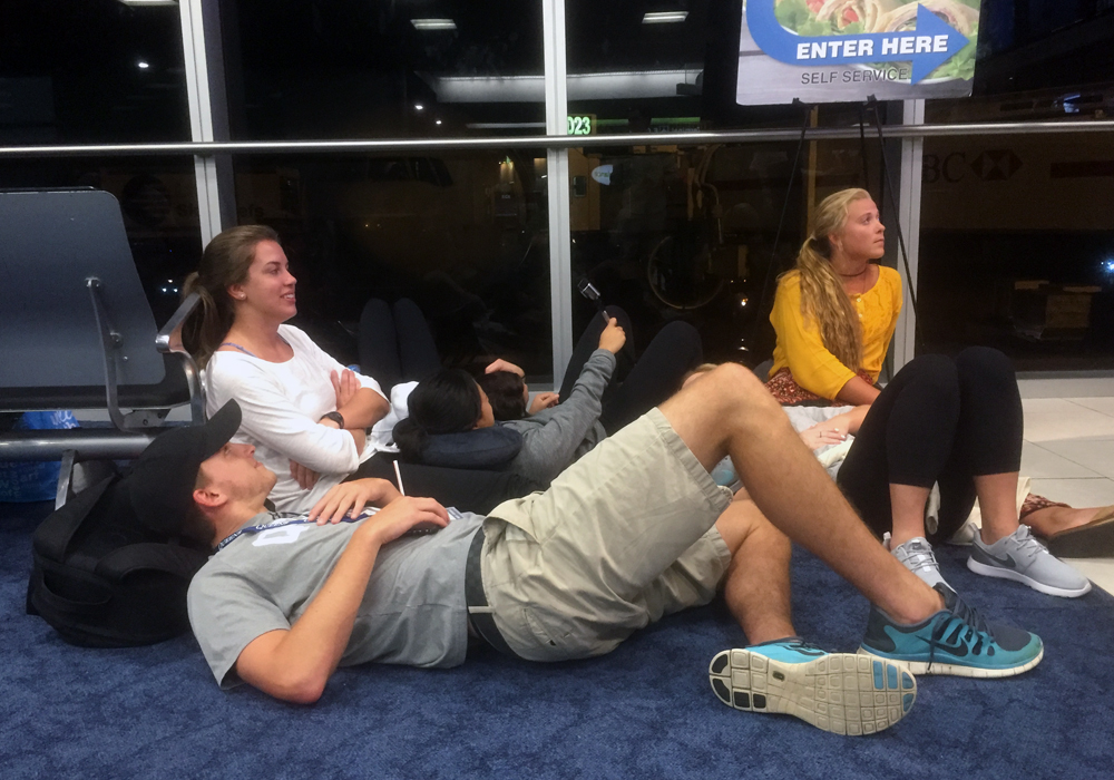 Queens students Austin Huddy, Abby Tolar, Becca Chen (selfie stick), and Kelsey McCormick watch opening ceremonies of the Rio 2016 Olympic Games on a layover at Miami airport, Aug. 5, 2016.